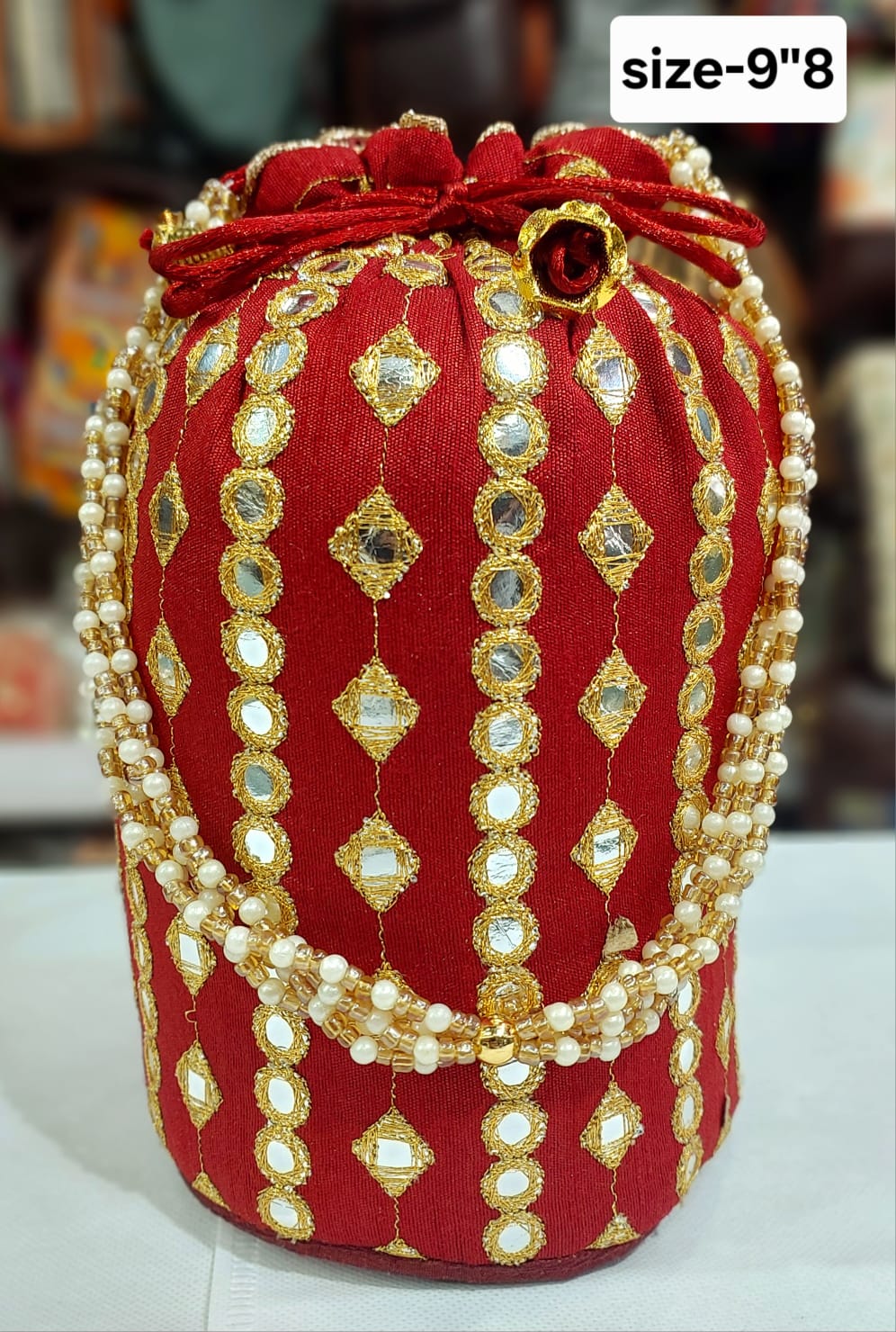 Red and gold embroidered work potli bag with pearl handle